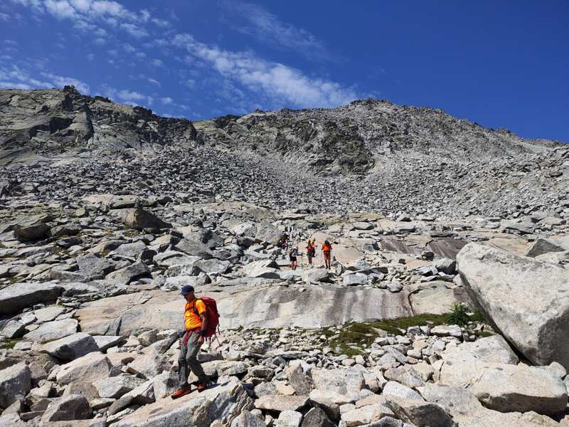 Il gruppo scende sulle placche e sui massi, sotto il versante di pietre
